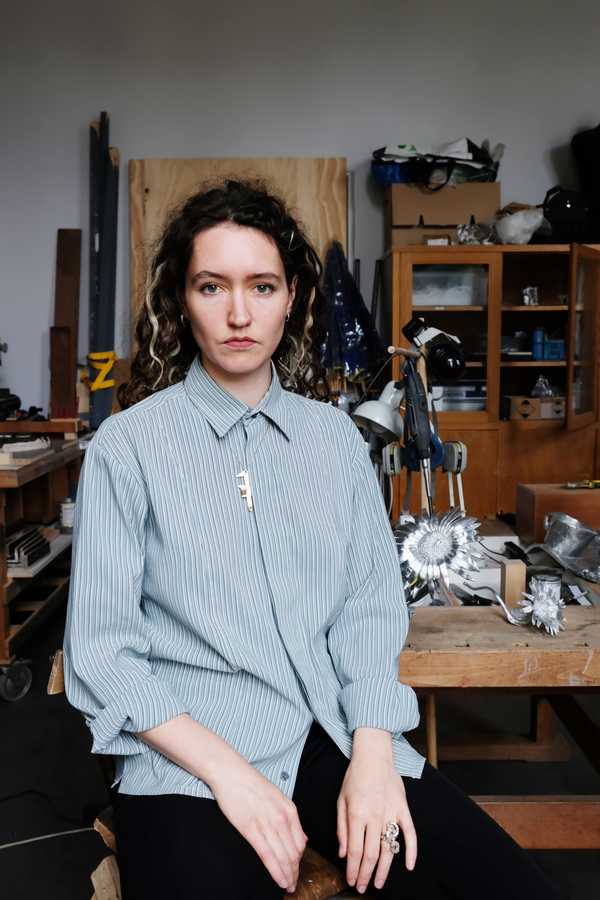 portrait of olga in her atelier holding sculptures